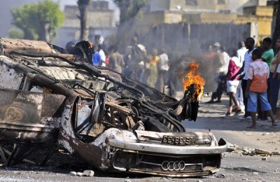Um carro arde e populares protestam no bairro de Benfica, subúrbio de Maputo. Foto de ANTONIO SILVA / LUSA