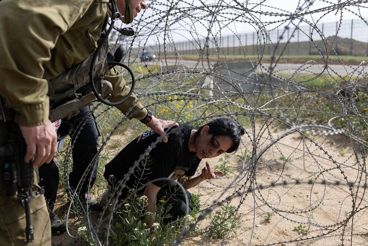 Einav Zangauker rasteja sob a barreira de arame farpado junto à fronteira com Gaza, protestando contra o recomeço da guerra de Israel, 18 de março de 2025.
