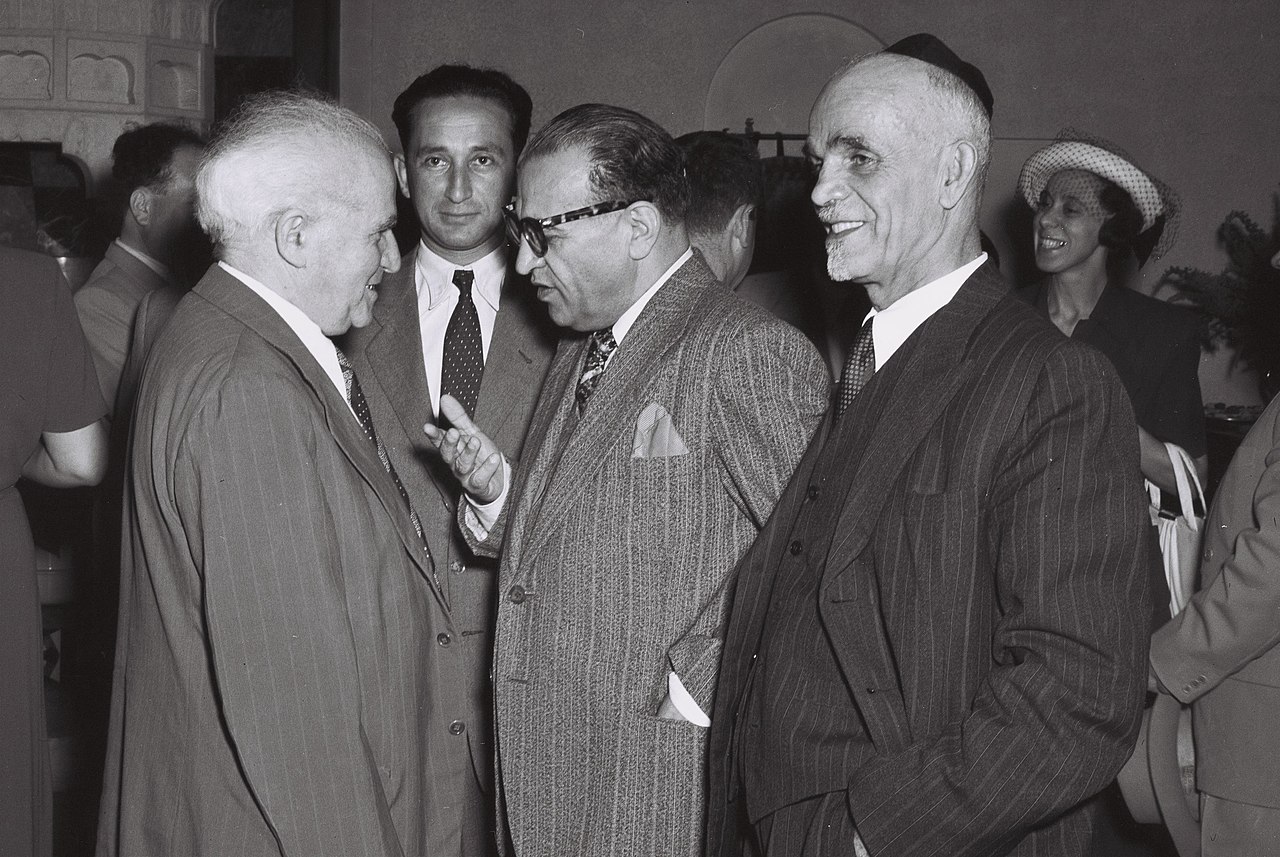 Reza Saffinia conversa com David Ben-Gurion e Shmuel Divon durante o cocktail oferecido pela delegação iraniana no edifício da Y.M.C.A. em Jerusalém. junho de 1950 