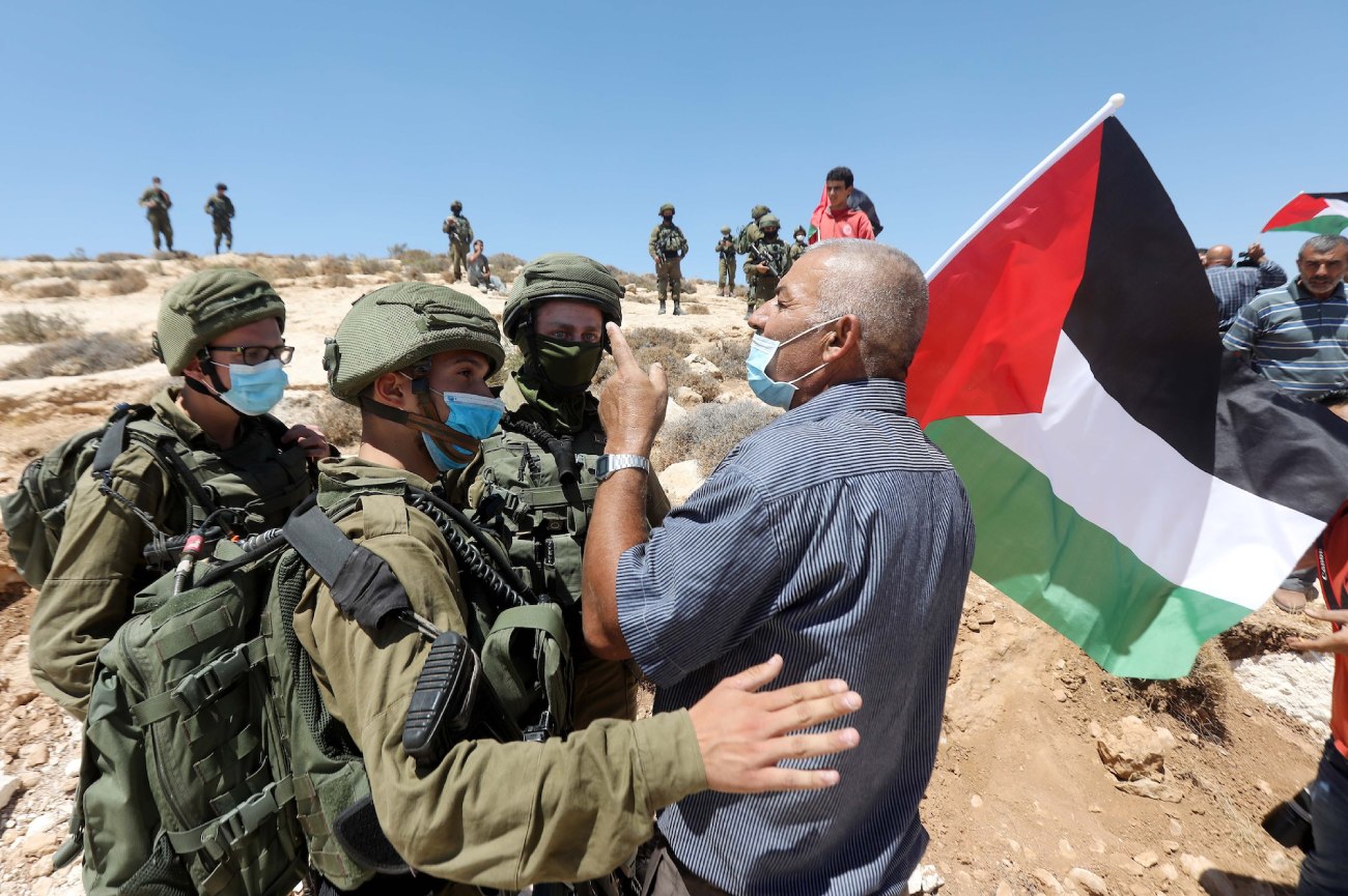 Soldados israelitas confrontam um manifestante palestiniano durante um protesto contra a construção de colonatos israelitas na aldeia de Al-Thaalaba, perto de Yatta, na Cisjordânia, em 21 de agosto de 2020. (Wissam Hashlamoun/Flash90)
