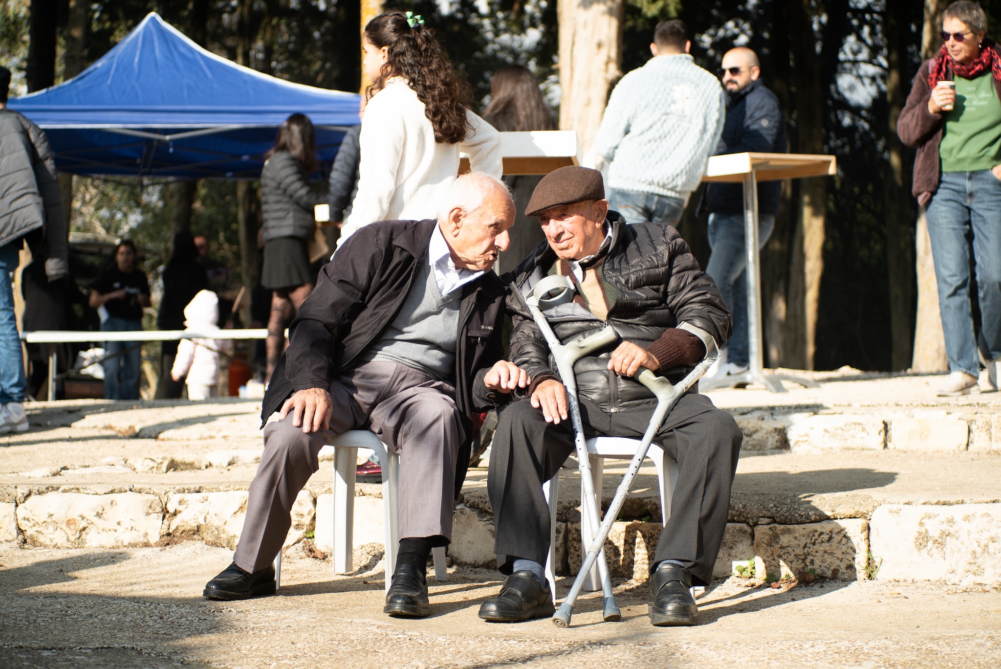 Ibrahim Eissa (à esquerda) senta-se com um amigo no mercado de Natal em Bir'im, em 13 de dezembro de 2025.