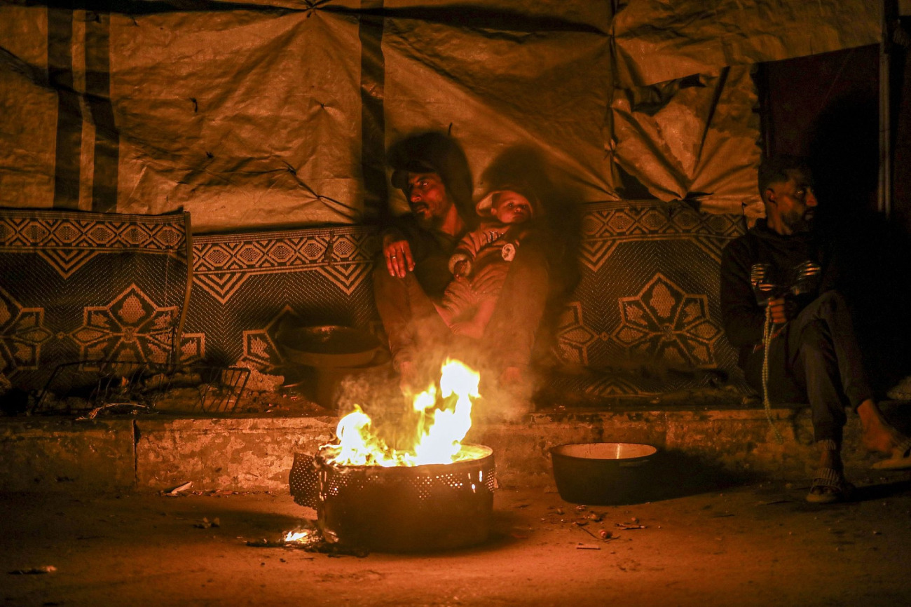 Famílias palestinianas deslocadas tentam manter-se aquecidas na rua Rashid, na cidade de Gaza, em 23 de janeiro de 2026.