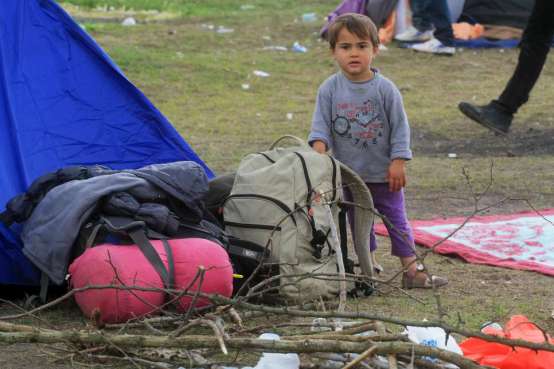 Menino afegão mostra os haveres da sua família em frente a uma tenda de campanha, perto de Röszke, na Hungria. Foto: Zsolt Balla/© Alto Comissariado para os Refugiados