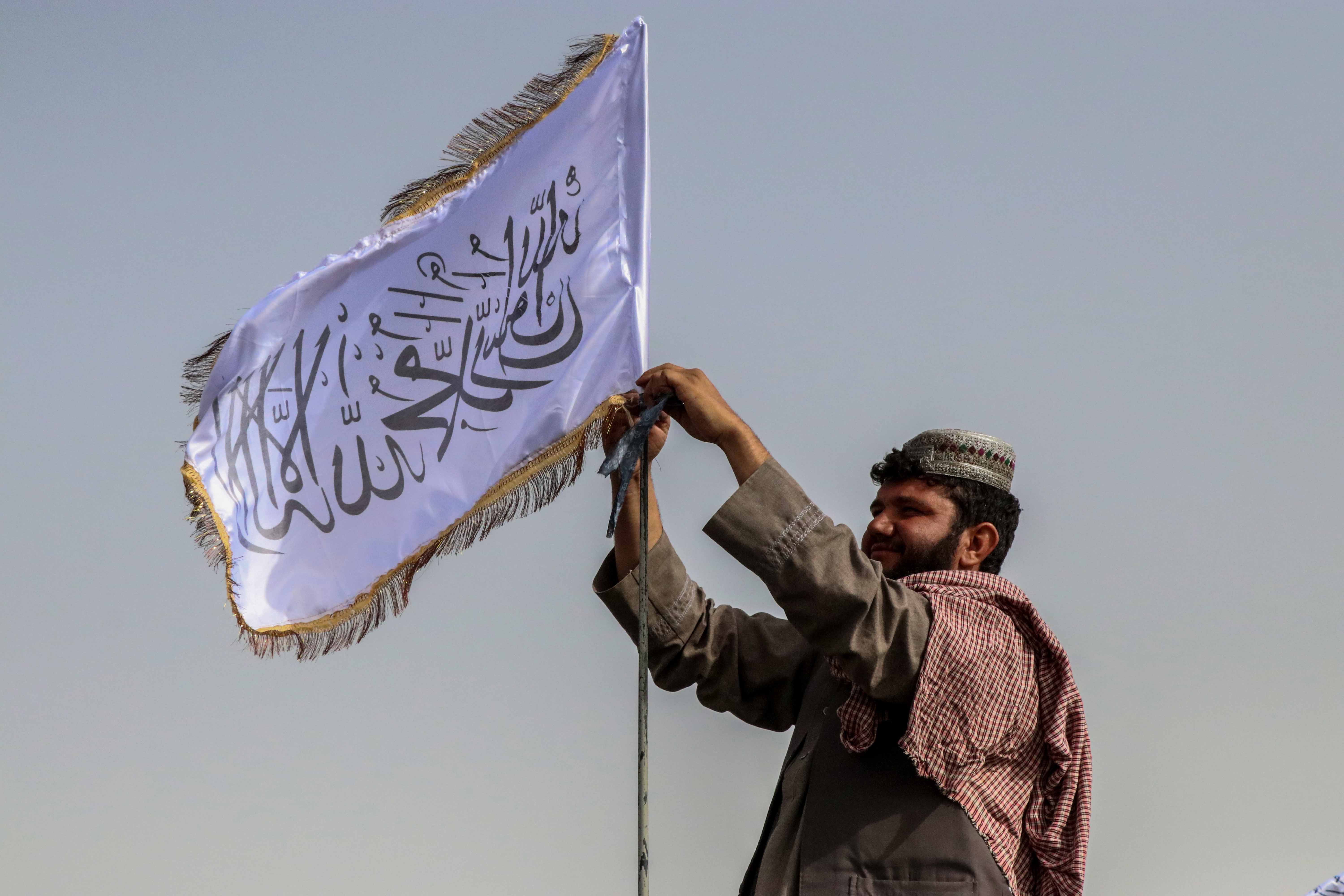 Combatente talibã ergue a sua bandeira num veículo em Kandahar. Foto de STRINGER/EPA/Lusa.