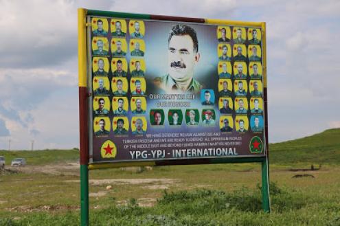 Cartaz no Curdistão sírio em que se pode ver o líder do PKK, Abdullah Öcalan ladeado por mártires combatentes, as siglas das unidades curdas da síria (YPG e YPJ) e a frase: "Os nossos mártires são a nossa honra". Neste cartaz a Turquia é classificada como fascista. Fotografia: José Manuel Rosendo/Abril 2019