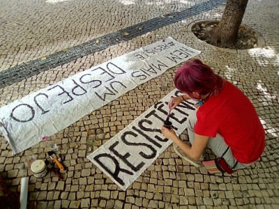 Ativista pinta um cartaz contra despejos. Foto do facebook da Habita.