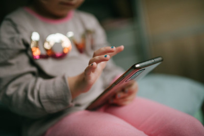 Criança ao telemóvel. Foto de Nenad Stojkovic.