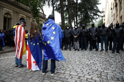 Manifestantes georgianos com bandeiras do seu país, dos EUA e da UE em protesto.