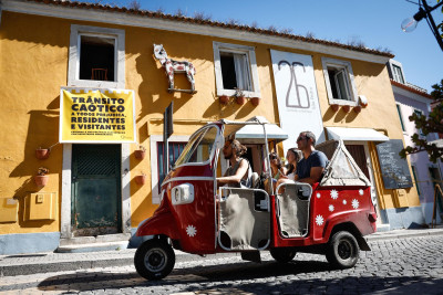 Tuk tuk em Sintra com cartaz de protesto em pano de fundo