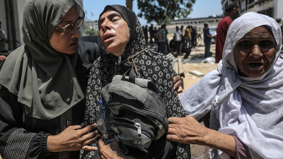 Uma mãe palestiniana chora abraçada à mochila do filho, morto por soldados israelitas quando tentava buscar comida no ponto de ajuda humanitária de Zikim.