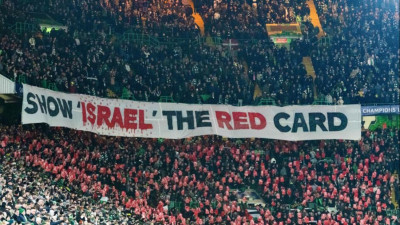 A claque do Celtic de Glasgow Green Brigade exibe uma faixa onde se lê "Mostrem o cartão vermelho a Israel"