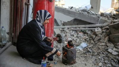 Uma mulher cozinha em Gaza no meio de ruínas, numa imagem captada em setembro de 2024. 