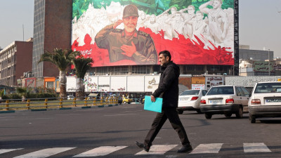 Uma pessoa passa por um outdoor com a imagem do ex-comandante da Força Quds do Corpo da Guarda Revolucionária Islâmica do Irão (IRGC), Qasem Soleimani, no centro de Teerão, Irão, em 6 de janeiro de 2026. 
