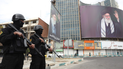 Forças de segurança iranianas montam guarda ao lado do enorme outdoor do líder supremo iraniano, aiatolá Ali Khamenei, na Praça Valiasr, em Teerão, Irão, 2 de março de 2026. 