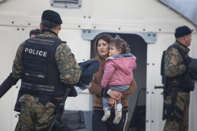 Mulher refugiada com criança abordada pela polícia local.