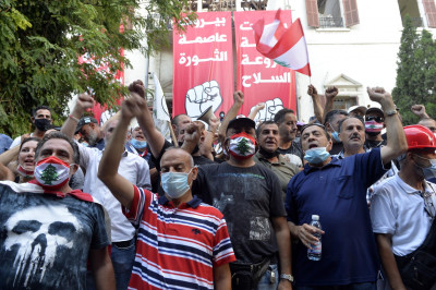 Manifestantes libaneses em frente a duas faixas de que dizem "Beirute Capital da Revolução" e "Beirute Capital sem armas". Agosto de 2020. Foto de WAEL HAMZEH/EPA/Lusa.