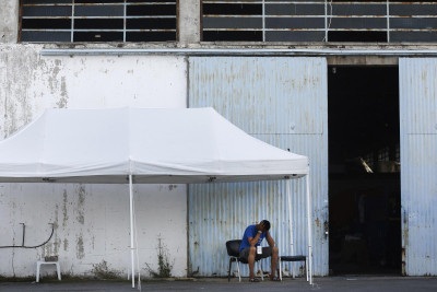 Sobrevivente do naufrágio à porta do armazém para onde foram levados. Foto de YANNIS KOLESIDIS/EPA/Lusa.
