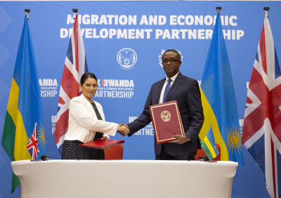 Priti Patel, secretária de Estado do Interior britânica com Vincent Biruta, ministro dos Negócios Estrangeiros do Ruanda no ato de assinatura do acordo. Abril de 2022. Foto de EUGENE UWIMANA/EPA.