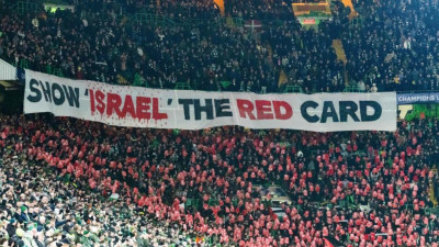 A claque do Celtic de Glasgow Green Brigade exibe uma faixa onde se lê "Mostrem o cartão vermelho a Israel"