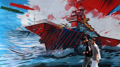 Jovens passam por um mural anti-EUA e Israel em Teerão.