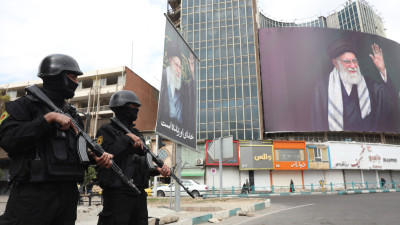 Forças de segurança iranianas montam guarda ao lado do enorme outdoor do líder supremo iraniano, aiatolá Ali Khamenei, na Praça Valiasr, em Teerão, Irão, 2 de março de 2026. 