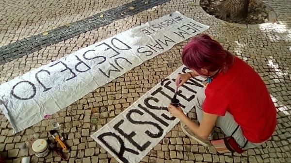 Ativista pinta um cartaz contra despejos. Foto do facebook da Habita.