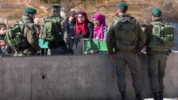 Raparigas palestinianas numa barreira policial em Hebron.
