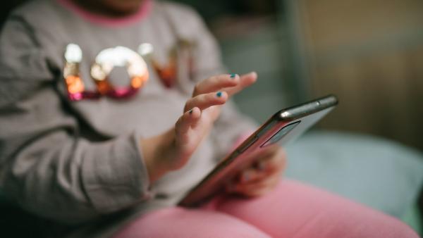 Criança ao telemóvel. Foto de Nenad Stojkovic.