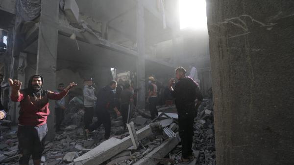 Palestinianos procuram corpos e sobreviventes nos escombros de um edifício residencial destruído por um ataque aéreo israelita, no campo de refugiados de Khan Younis, no sul da Faixa de Gaza,