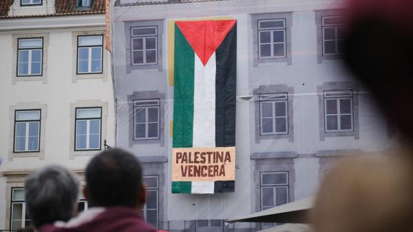 Bandeirão pendurado num edifício onde se lê Palestina Vencerá.