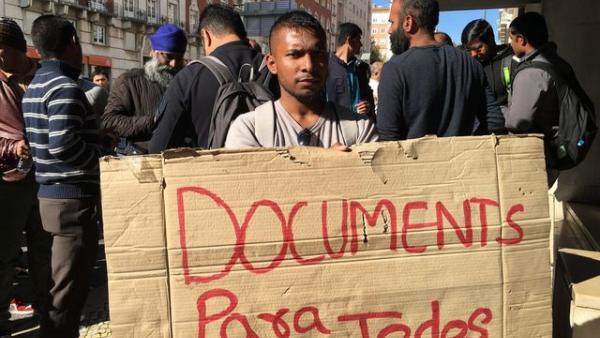 Imigrante com cartaz: documentos para todos