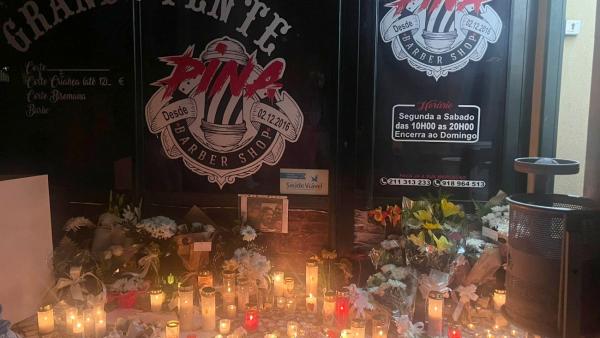 Velas e flores à porta da barbearia de Carlos Pina.