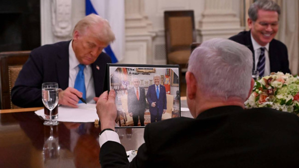 Netanyahu olha para uma foto com ele ao lado de Trump durante o encontro com o Presidente dos EUA.