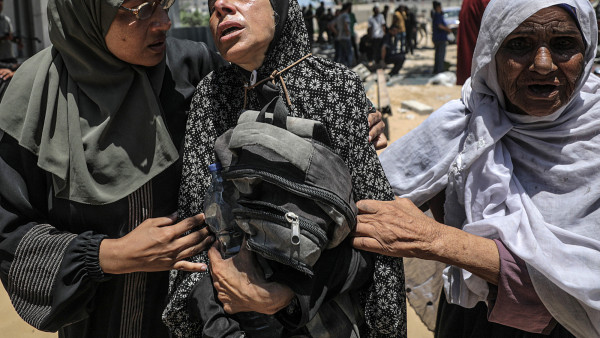 Uma mãe palestiniana chora abraçada à mochila do filho, morto por soldados israelitas quando tentava buscar comida no ponto de ajuda humanitária de Zikim.