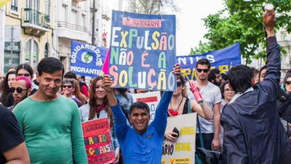 imigrante com cartaz "Expulsão não é a solução"
