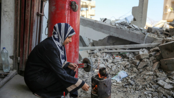 Uma mulher cozinha em Gaza no meio de ruínas, numa imagem captada em setembro de 2024. 