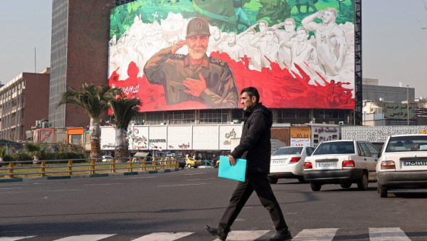Uma pessoa passa por um outdoor com a imagem do ex-comandante da Força Quds do Corpo da Guarda Revolucionária Islâmica do Irão (IRGC), Qasem Soleimani, no centro de Teerão, Irão, em 6 de janeiro de 2026. 