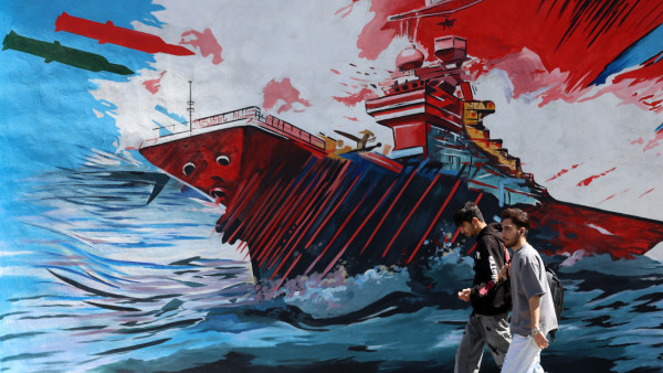 Jovens passam por um mural anti-EUA e Israel em Teerão.