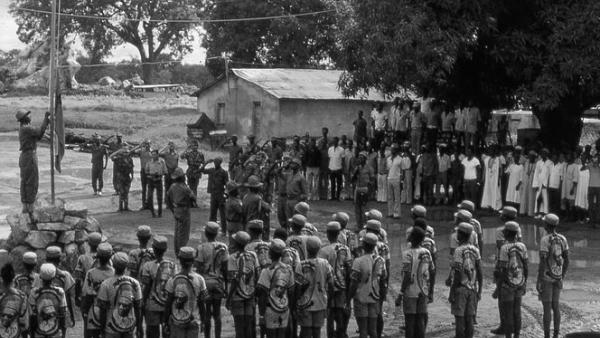 Hastear da bandeira da Guiné Bissau após o arrear da de Portugal em Canjadude. Foto (original a cores) de João Carvalho, Wikimedia - domínio público. 