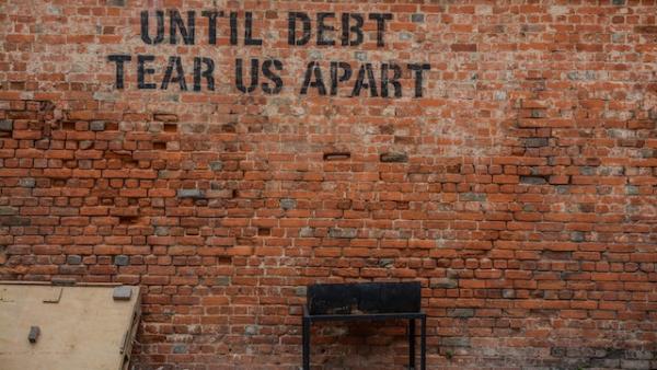 Parede com a frase: "Until debt tear us apart