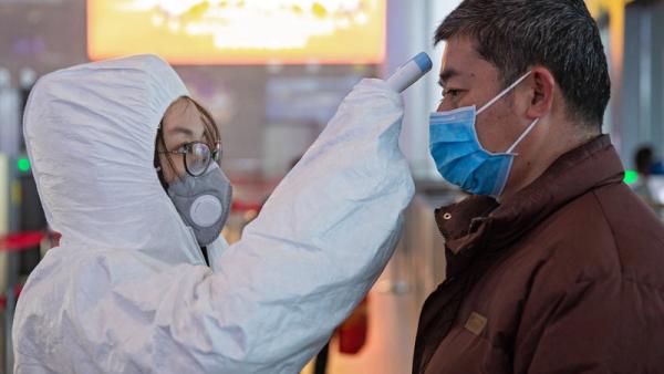 Equipas médicas tiram a temperatura aos passageiros na estação ferroviária de Nanjing, China. 