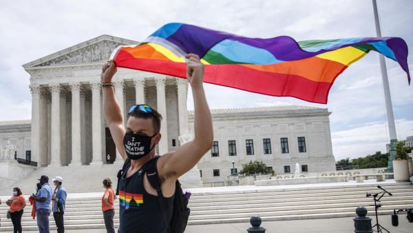 Homem celebra a decisão do Supremo Tribunal dos EUA com bandeira arco-íris à porta desta instituição. Foto de SHAWN THEW/EPA/Lusa.