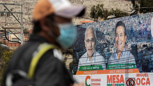 Um homem passa em frente a um cartaz do candidato de direita às eleições bolivianas. Foto de Joedson Alves/EPA/Lusa.
