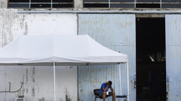 Sobrevivente do naufrágio à porta do armazém para onde foram levados. Foto de YANNIS KOLESIDIS/EPA/Lusa.