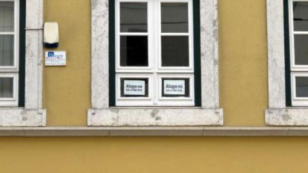Anúncio de casa para arrendar colado numa janela.