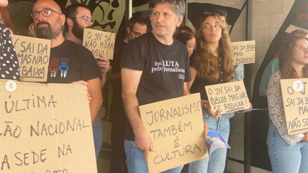 Trabalhadores do Jornal de Notícias à porta da sede do jornal com cartazes nas mãos.