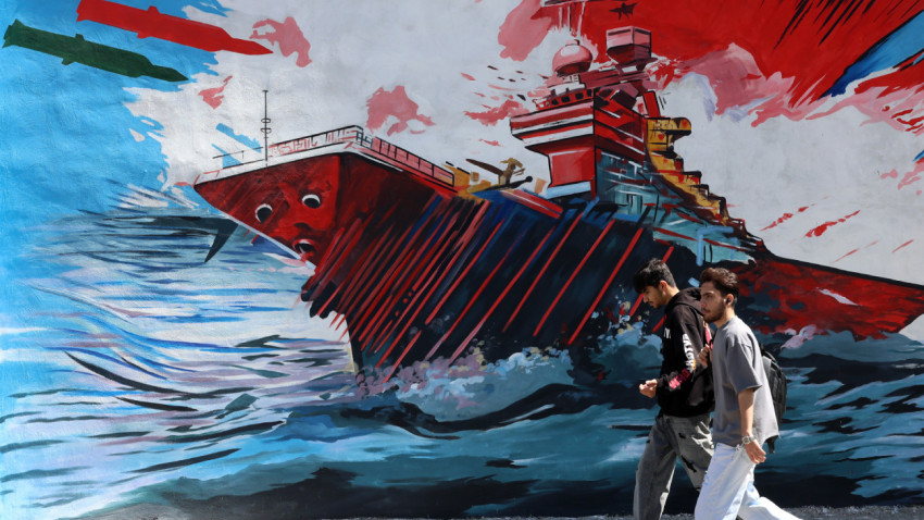 Jovens passam por um mural anti-EUA e Israel em Teerão.