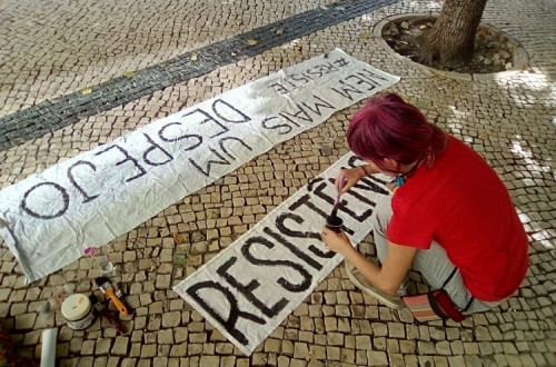 Ativista pinta um cartaz contra despejos. Foto do facebook da Habita.
