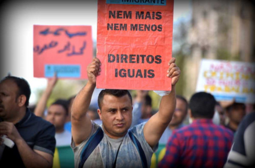 Imigrante: Nem mais, nem menos - Direitos Iguais", imigrante com pancarta na manifestação do 1º de Maio de 2016