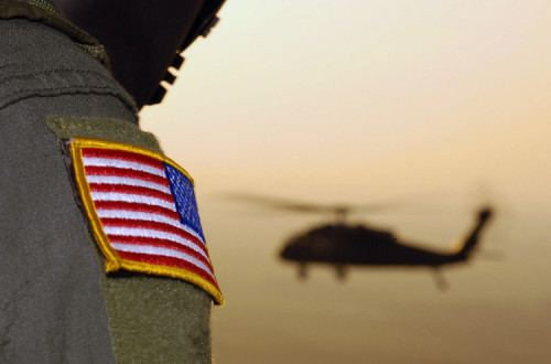 Soldado com um símbolo do exército norte-americano com um helicóptero no fundo.